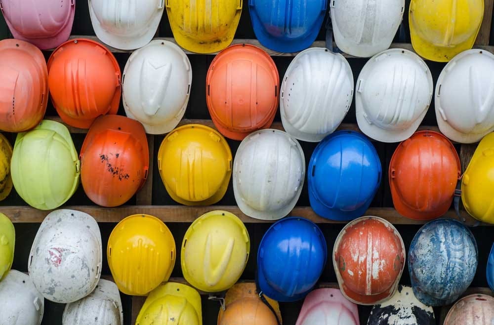 cascos de construcción de varios colores colgados de la pared